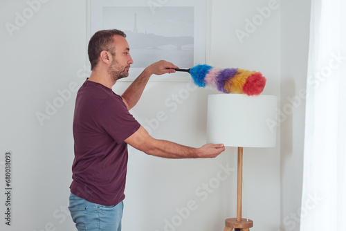 Wall Mural Man cleaning apartment with dusting broom.