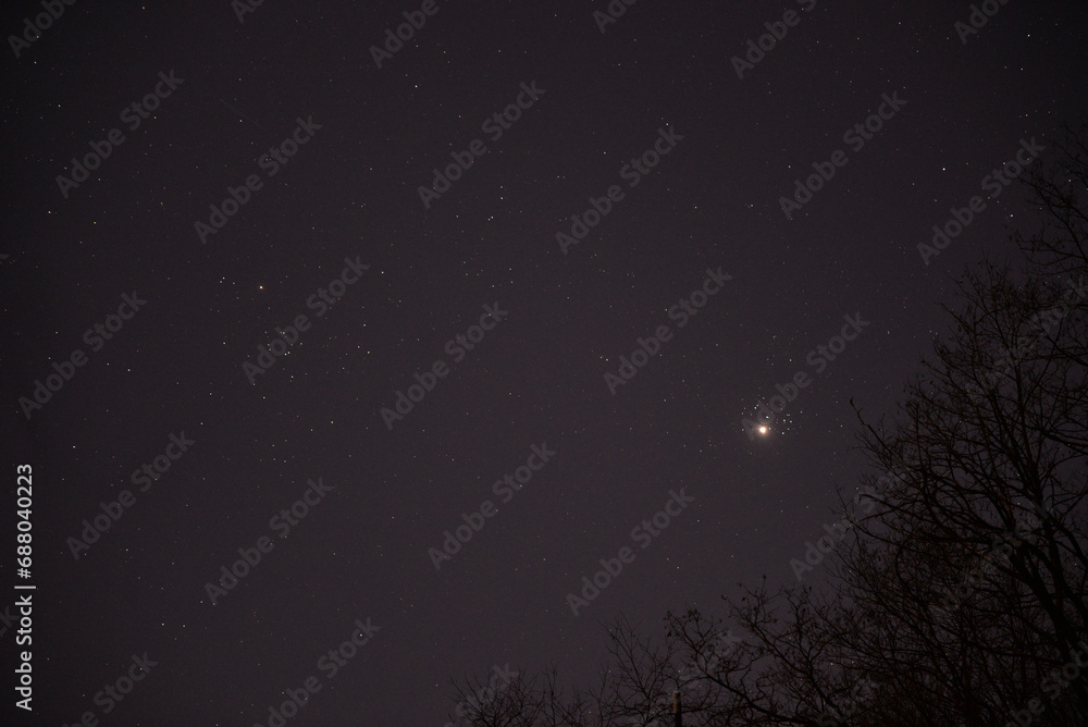 The planet Venus in the starry night sky in conjunction with the Pleiades Constellation. The group of stars The seven sisters observed from a dark place