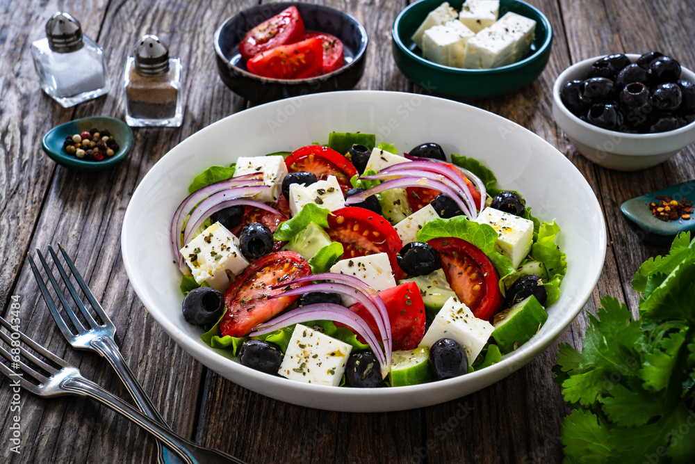 Greek style salad - fresh vegetables with feta cheese on wooden table
Greek style salad - fresh vegetables with feta cheese on wooden table