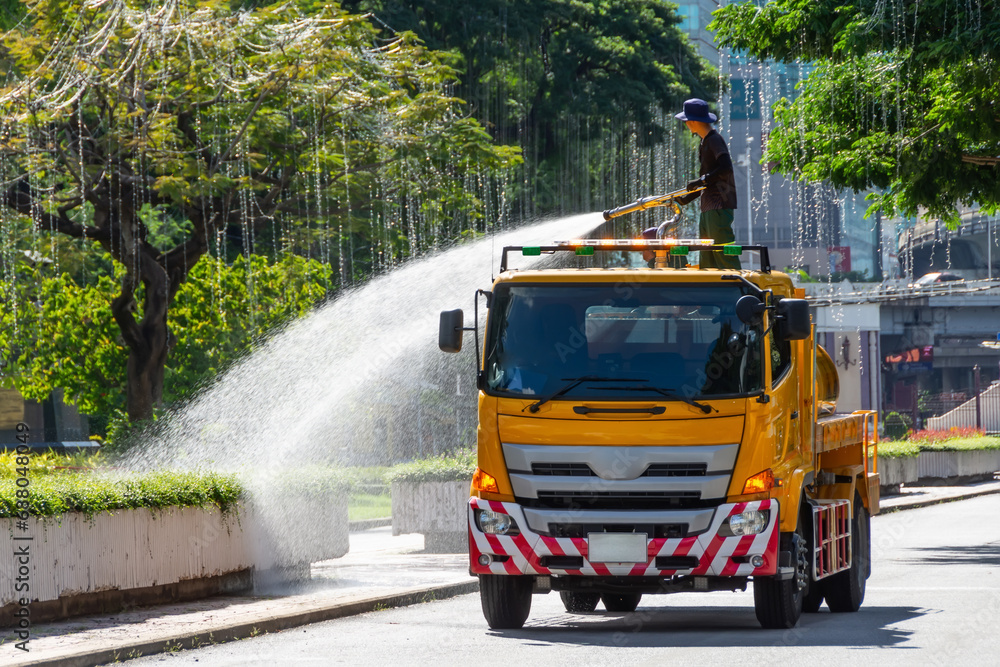 Truck with a water tank waters plants and flowers from a fire hose, a city park worker