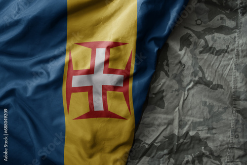 waving flag of madeira on the old khaki texture background. military concept.