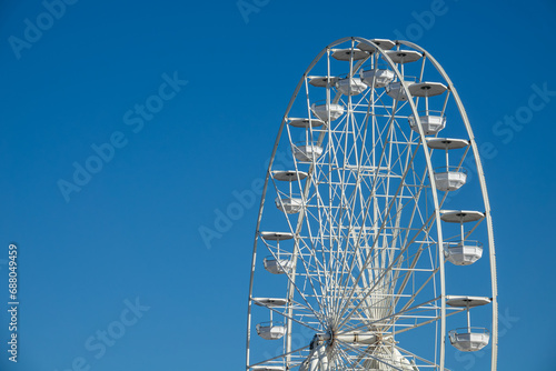 Big, tall white Ferris wheel. Modern ferris wheel at carnival with blue sky