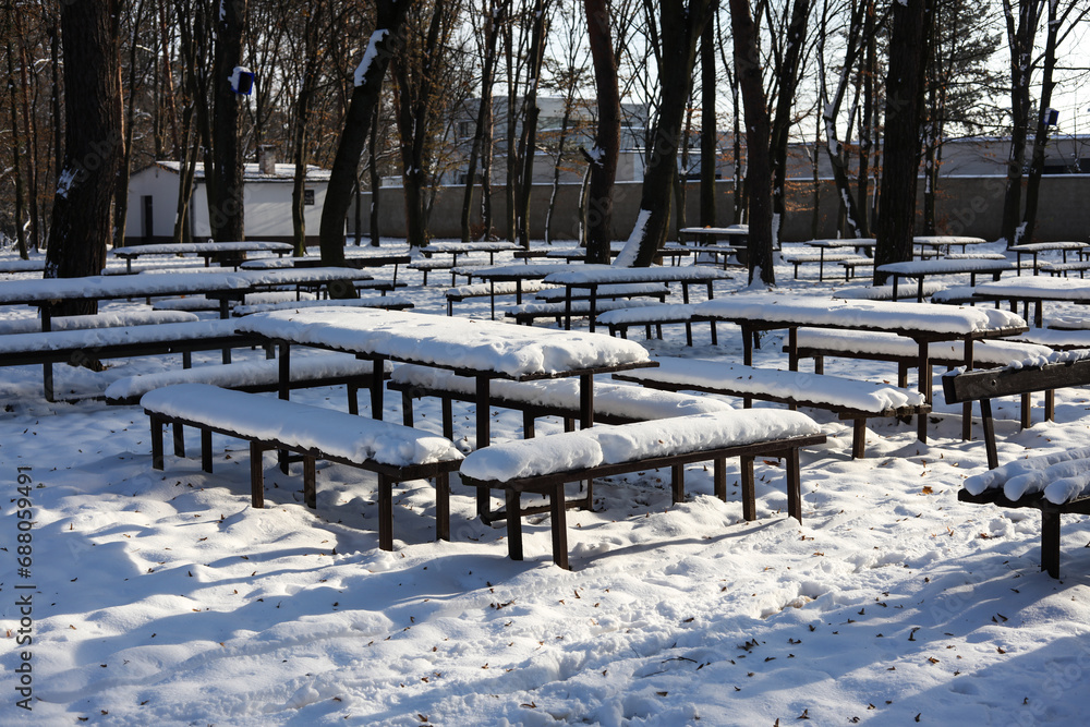 picnic tables in the park covered in snow 