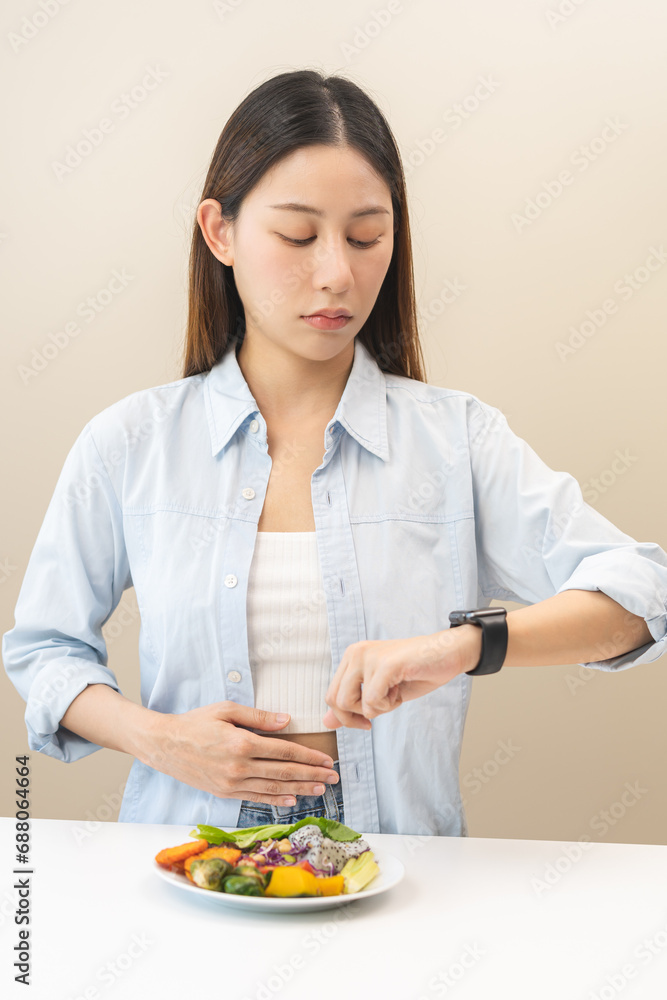 Intermittent fasting, diet healthy asian young woman dietary, having stomach ache, temptation hungry of brunch food in morning on table at home, waiting time to eat salad but not yet time first meal. Intermittent fasting, diet healthy asian young woman dietary, having stomach ache, temptation hungry of brunch food in morning on table at home, waiting time to eat salad but not yet time first meal.