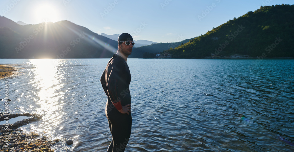 Authentic triathlon athlete getting ready for swimming training on lake Authentic triathlon athlete getting ready for swimming training on lake