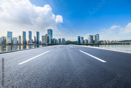 Asphalt highway road and city skyline with modern buildings under blue sky