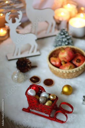 Cup of tea or coffee  glass of wine or juice  bowl of cookies  organic pomegranate  fluffy blanket  pine cones  various Christmas decorations and lit candles on the table. Christmas hygge concept.