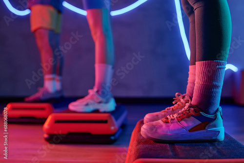 Legs of unrecognizable gym goers calmly standing on step platforms at fitness center, copy space