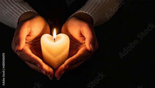 Hands holding burning candle in dark like a heart.black background.Copy space.