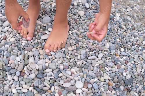 Child's feet and hands engage with a myriad of stones, illustrating active discovery.