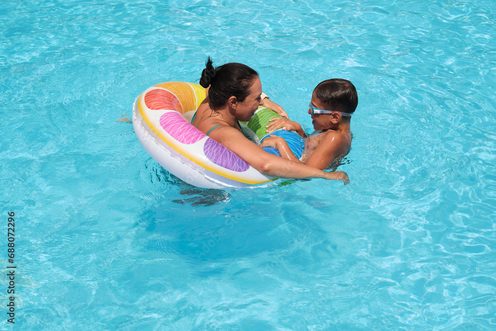 Water splashes around a fun float; mother and child bonding. Emphasizes the importance of physical play in a digital age.
