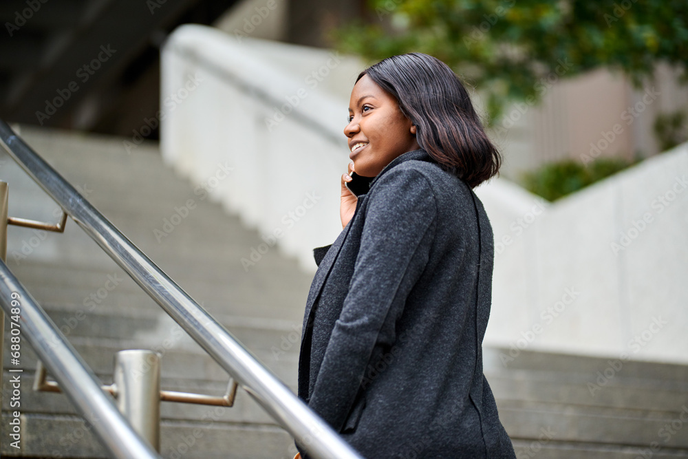 Young Black career woman walking up stairs outside while talking on the phone Young Black career woman walking up stairs outside while talking on the phone