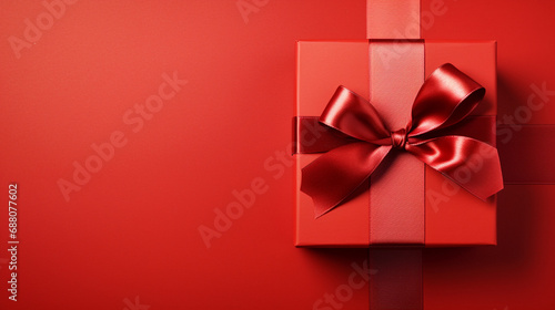 red gift box with satin ribbon and bow on red background