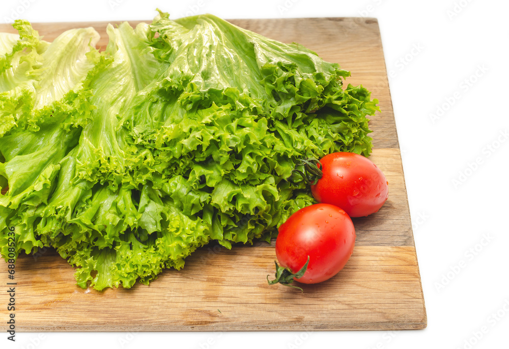 Two red cherry tomatoes and green lettuce on a wooden board. Vegan food. Salad preparation. Two red cherry tomatoes and green lettuce on a wooden board. Vegan food. Salad preparation.
