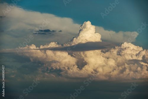 Cumulus congestus clouds climbing dramatically into a late summer afternoon sky before a background of a cumulonimbus cloud
