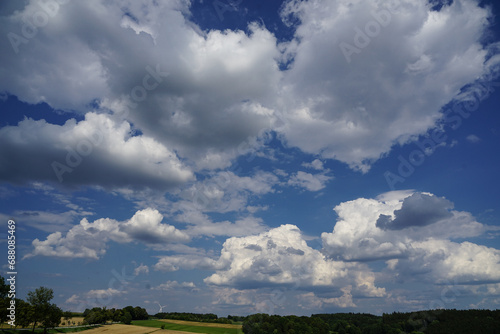 Friendly blue summer sky with scattered cumulus clouds over a rural countryside with a very low horizon