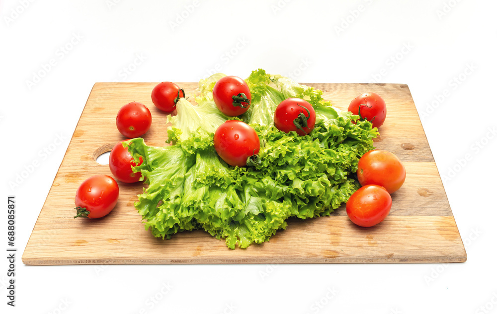 Bright red cherry tomatoes and green lettuce on a wooden board. Vegan food. Salad preparation. Bright red cherry tomatoes and green lettuce on a wooden board. Vegan food. Salad preparation.