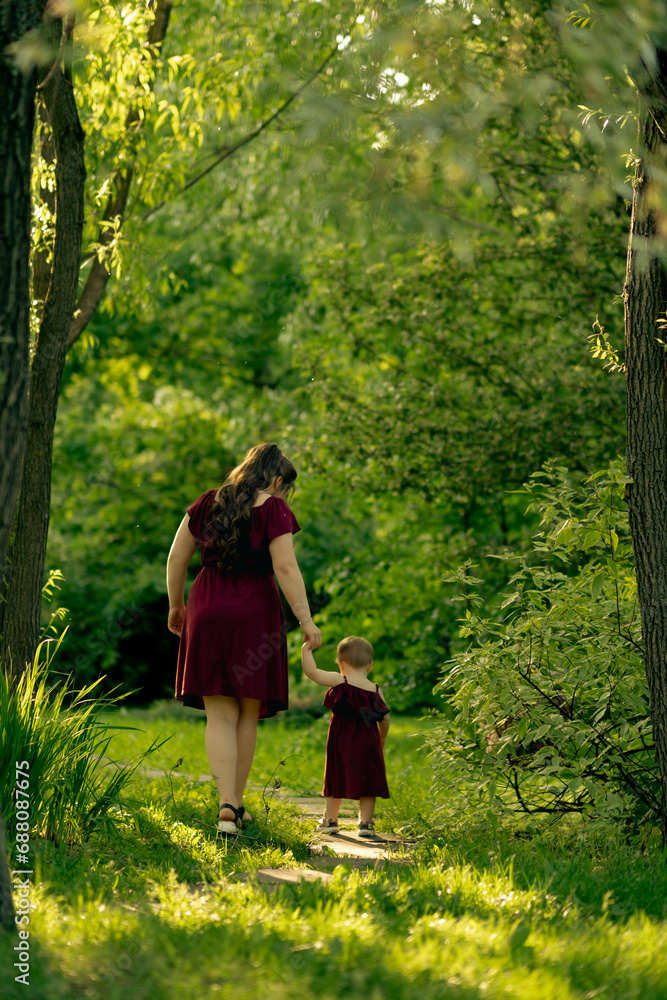 Amid the serenity of nature, a mother and her child take steps together in harmony, a dance of shadows and light playing around them. Amid the serenity of nature, a mother and her child take steps together in harmony, a dance of shadows and light playing around them.