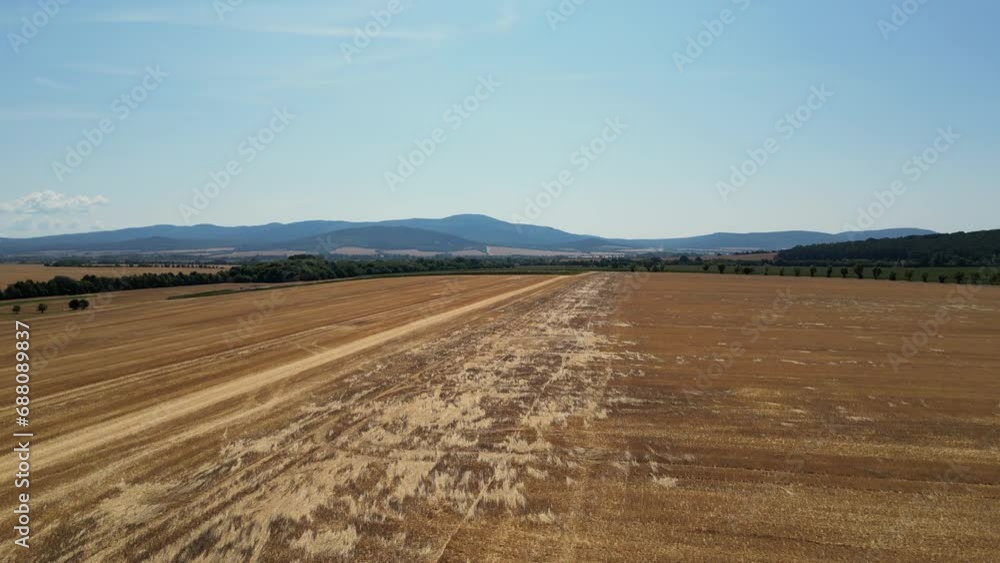 Flying over tractor with harrow system plowing ground on cultivated farm field. Industrial footage on agricultural theme. Agriculture in European country Slovakia. Blue Mountains in the background. Flying over tractor with harrow system plowing ground on cultivated farm field. Industrial footage on agricultural theme. Agriculture in European country Slovakia. Blue Mountains in the background.