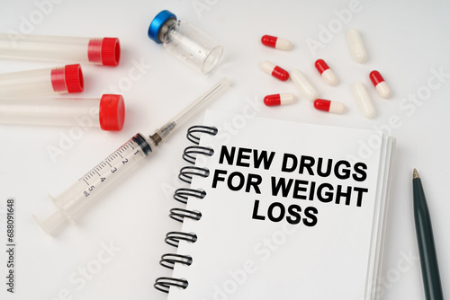 On the table are pills, injections, a syringe and a notepad with the inscription - new drugs for weight loss