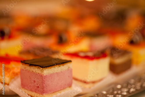 This image offers a glimpse of a dessert tray filled with an assortment of petit fours, captured in a soft focus that creates a dreamy, indulgent atmosphere. The blurred effect draws attention to the
