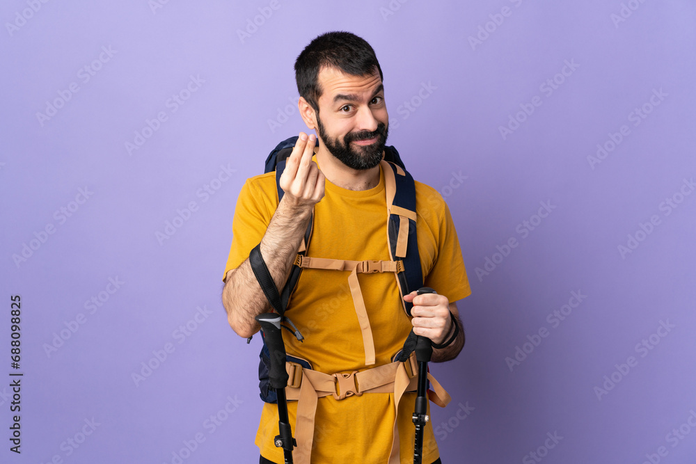 Caucasian handsome man with backpack and trekking poles over isolated background making money gesture Caucasian handsome man with backpack and trekking poles over isolated background making money gesture