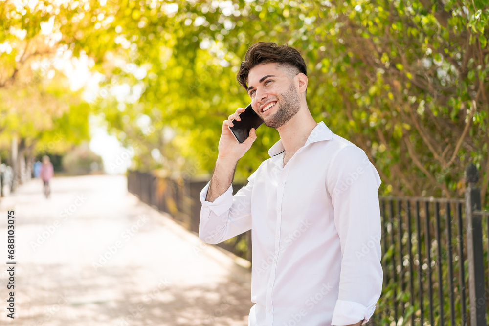 Young handsome man at outdoors keeping a conversation with the mobile phone Young handsome man at outdoors keeping a conversation with the mobile phone