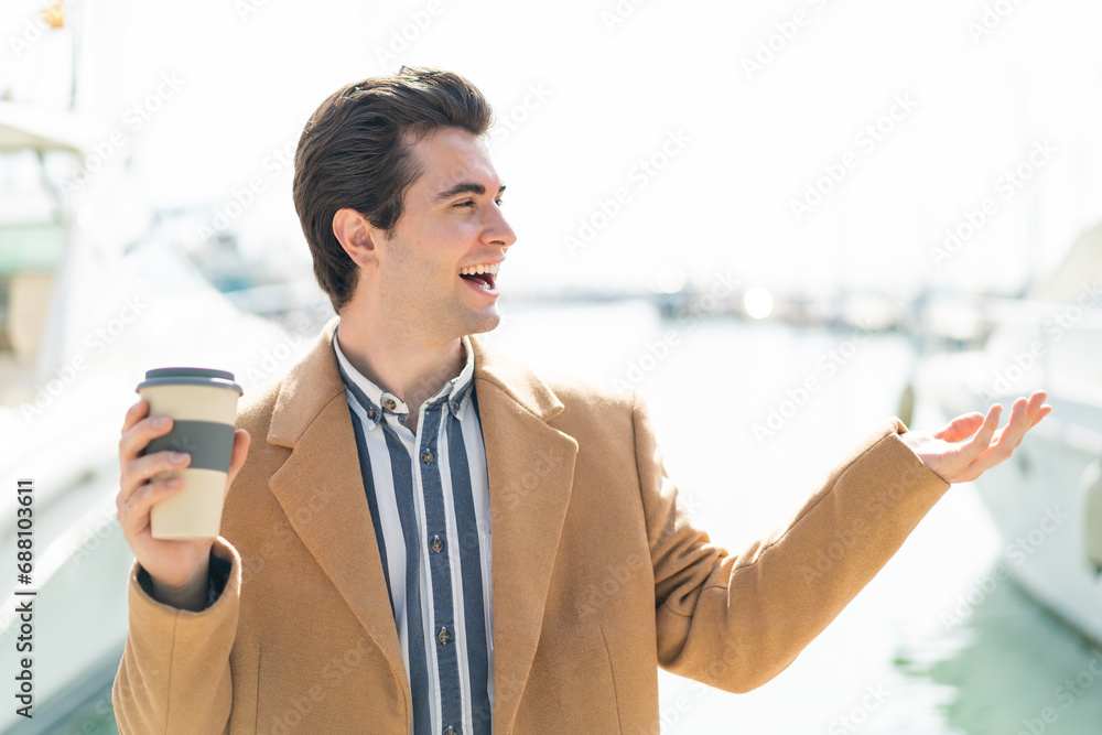 Young handsome man holding a take away coffee at outdoors with surprise facial expression Young handsome man holding a take away coffee at outdoors with surprise facial expression