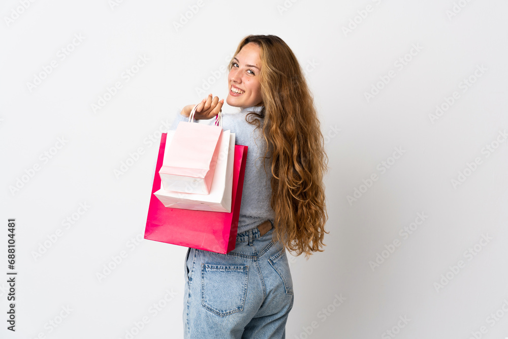 Fototapeta premium Young blonde woman isolated on white background holding shopping bags and smiling