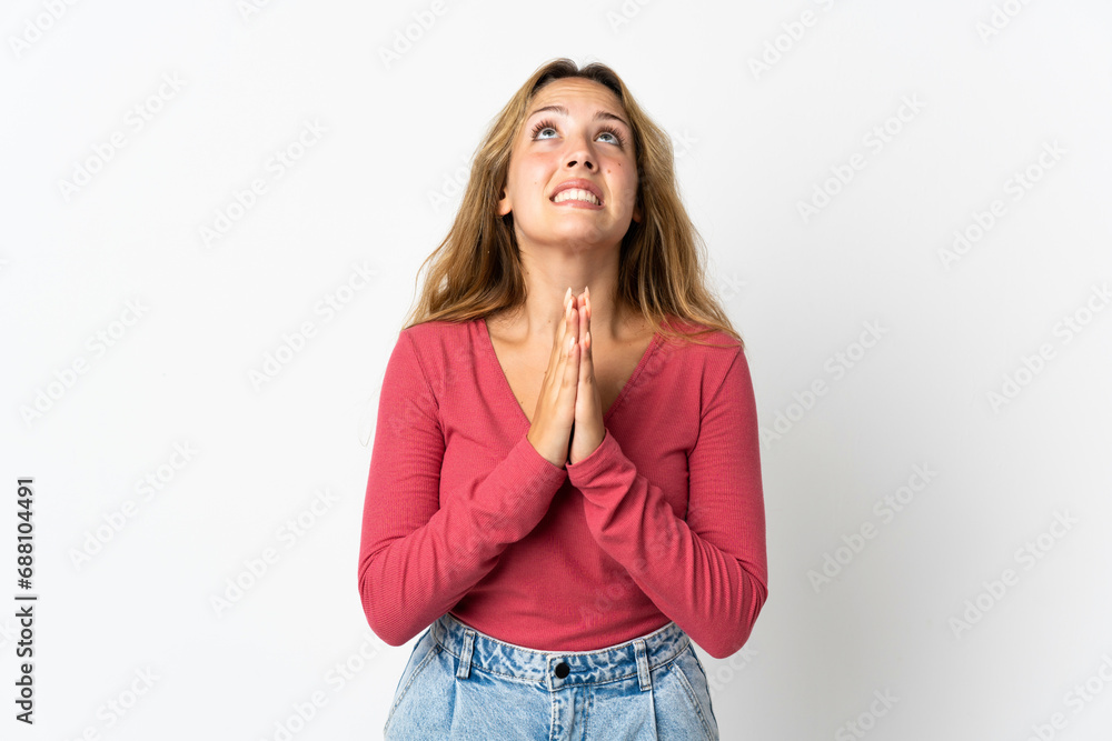 Young blonde woman isolated on blue background keeps palm together. Person asks for something