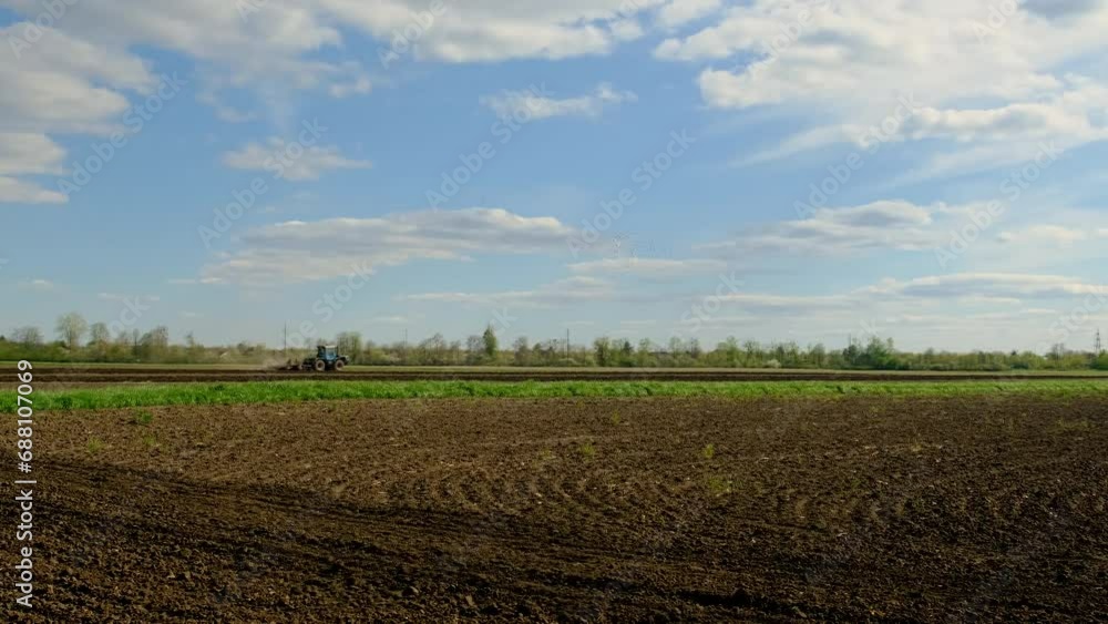 A tractor plows the ground in the field. Selective focus. A tractor plows the ground in the field. Selective focus.