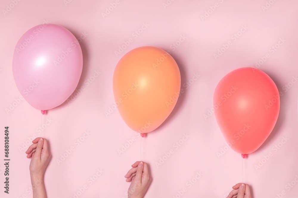 Pastel pink and colorfool balloons with females hands. Party concept.