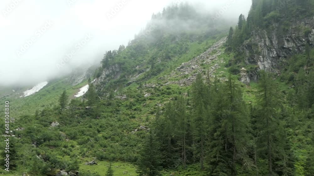 Clouds drift like mist along the mountain slopes of the Austrian Alps in Tyrol, creating a foggy atmosphere in the forested landscape. Clouds drift like mist along the mountain slopes of the Austrian Alps in Tyrol, creating a foggy atmosphere in the forested landscape.