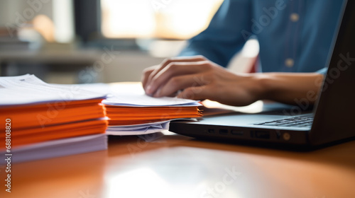 Close-up of a man working with a stack of documents and reports on his office desk