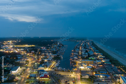 an aerial shot along the coastline of the Atlantic ocean with blue water  a sandy beach  hotels and condominiums and cars on the street at night with lights in Carolina Beach North Carolina USA