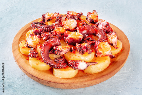 Pulpo a la gallega, Spanish octopus snack, Galician dish, in the traditional wooden plate on a slate background photo