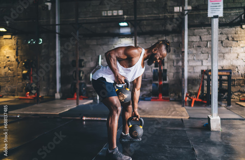 Black athlete exercising with kettlebell in gym
