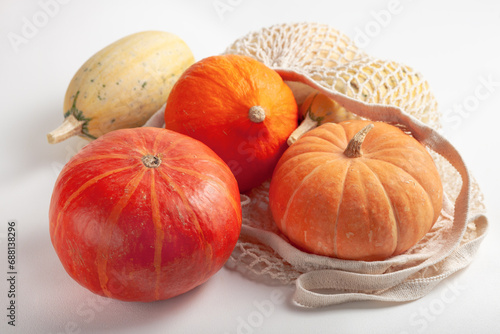 Different varieties of pumpkins in a string bag on a white background