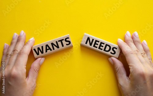 Wants and Needs symbol. Concept word Wants and Needs on wooden blocks. Businessman hand. Beautiful yellow background. Business and Wants and Needs concept. Copy space photo