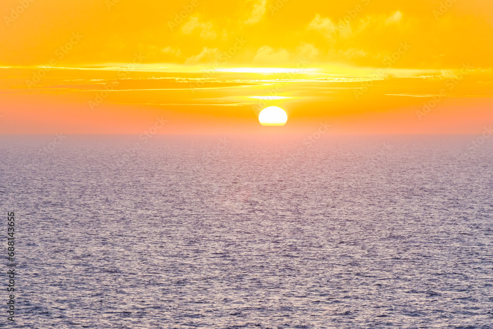 Beautiful Sunset in the Atlantic Ocean with orange sky and blue ocean somewhere in Faroe Islands
