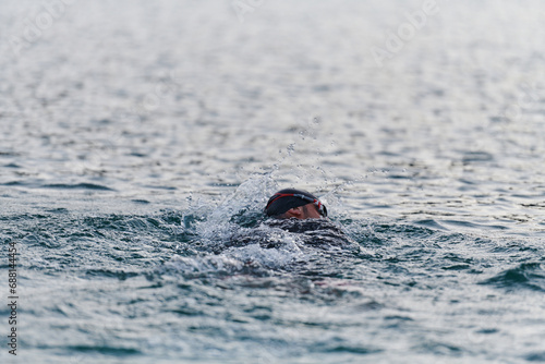 A professional triathlete trains with unwavering dedication for an upcoming competition at a lake, emanating a sense of athleticism and profound commitment to excellence.