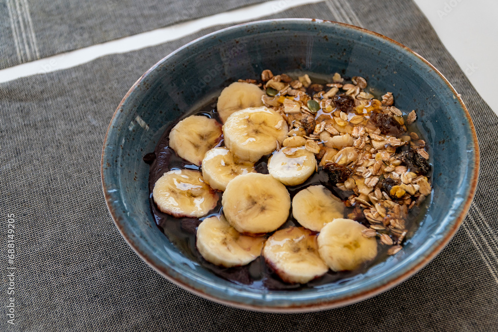 a bowl of healthy acai ice cream topped with banana oats and honey. a bowl of healthy acai ice cream topped with banana oats and honey.
