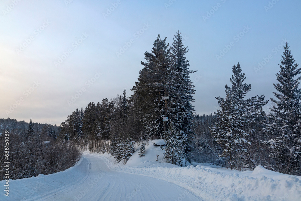 Obraz premium Winter landscape, road through a snowy forest. Winter travel.