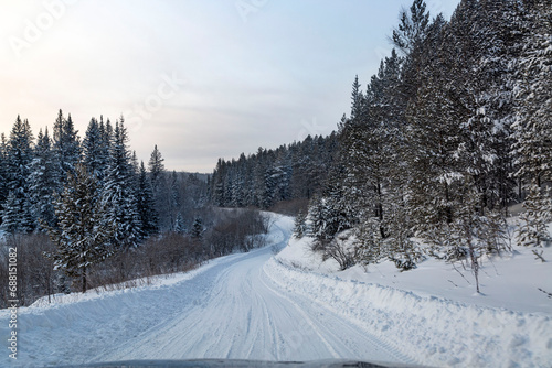 Winter landscape, road through a snowy forest. Winter travel.