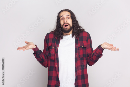 I do not know. Unaware perplexed bearded man spreads palms sideways, has no idea what to do, thinks how to act in troublesome situation. Indoor studio shot isolated on gray background.