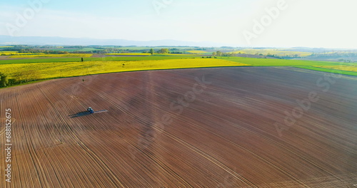 Farmer using tractor to spray field before planting.