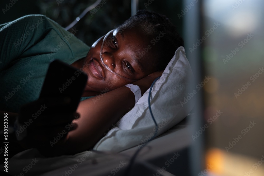 Patient in hospital room lies on her side, using the phone to watch videos. Patient in hospital room lies on her side, using the phone to watch videos.