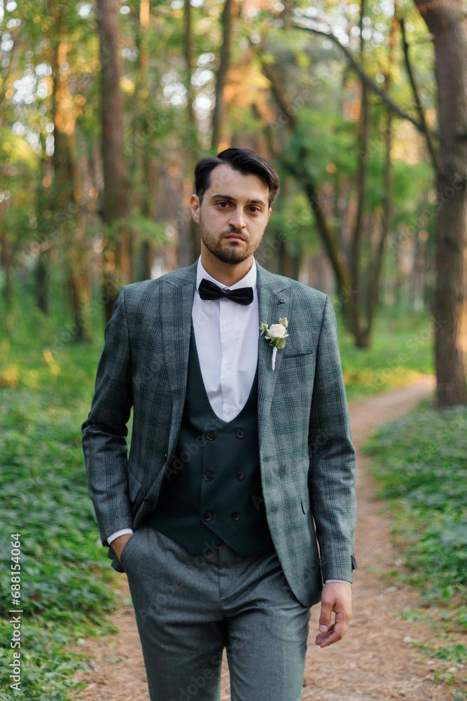 Beautiful couple, the groom in a green suit and the bride in an unusual pink wedding dress, posing at a luxurious ceremony with beautiful decor and an arch with a chandelier and candles in the forest Beautiful couple, the groom in a green suit and the bride in an unusual pink wedding dress, posing at a luxurious ceremony with beautiful decor and an arch with a chandelier and candles in the forest