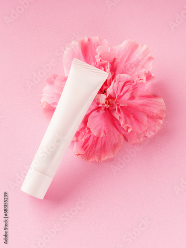 fleur rose sur fond rouge et rose, avec tube de crème