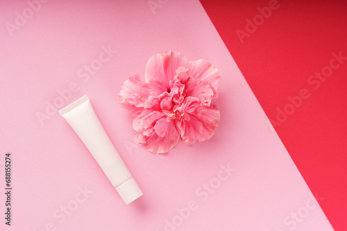 fleur rose sur fond rouge et rose, avec tube de crème